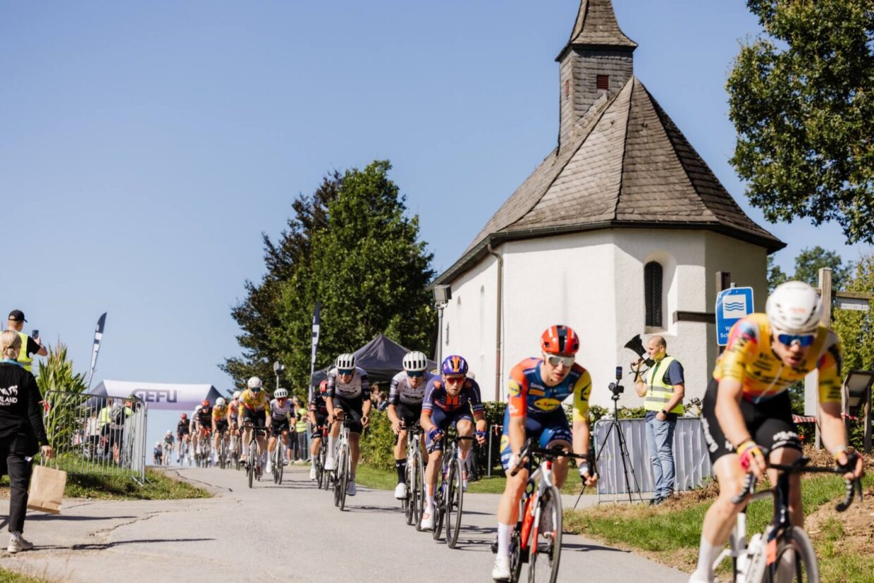 Rennradfahrer passieren eine Kappelle