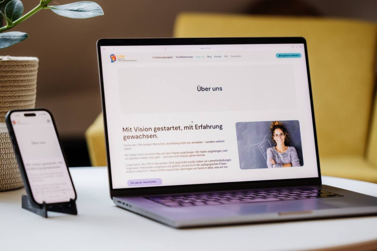 Ein Handy und ein Notebook stehen mit geöffnetem Browserfenster auf einem Couchtisch