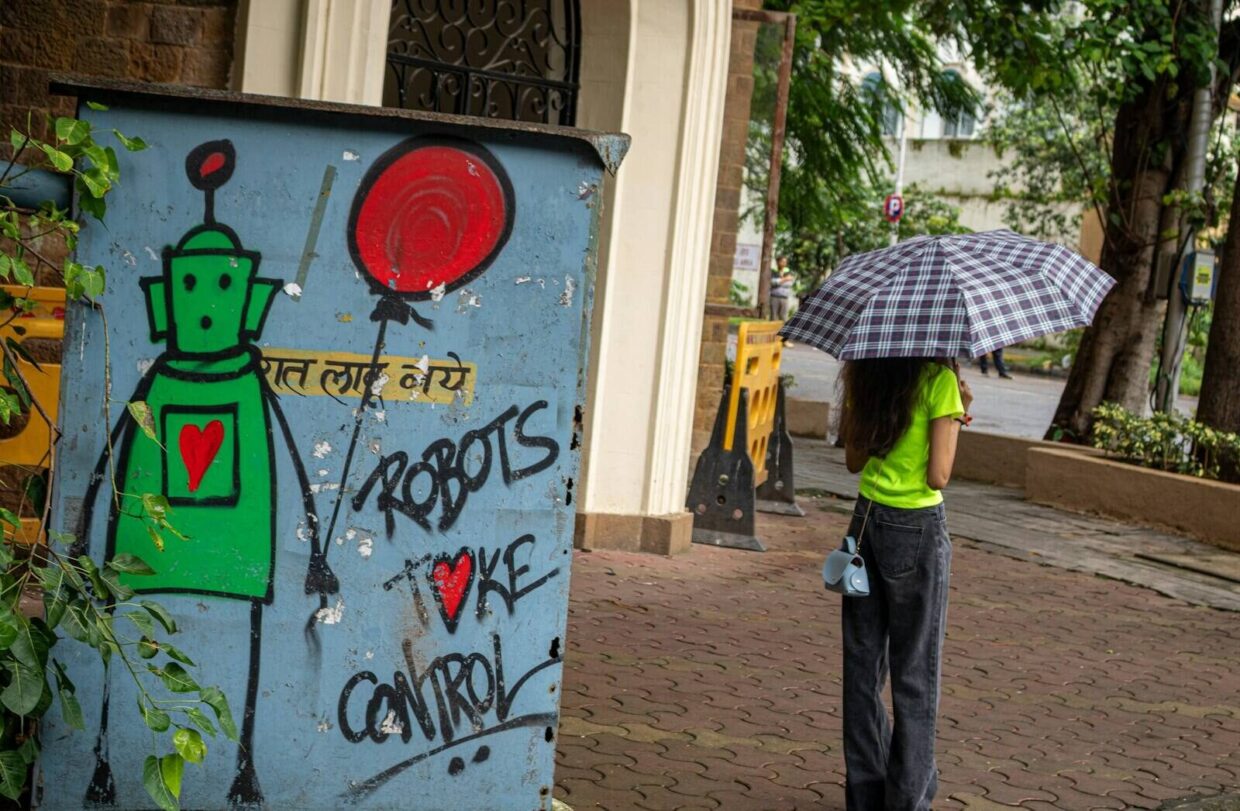 A person stands by robot graffiti in the rain